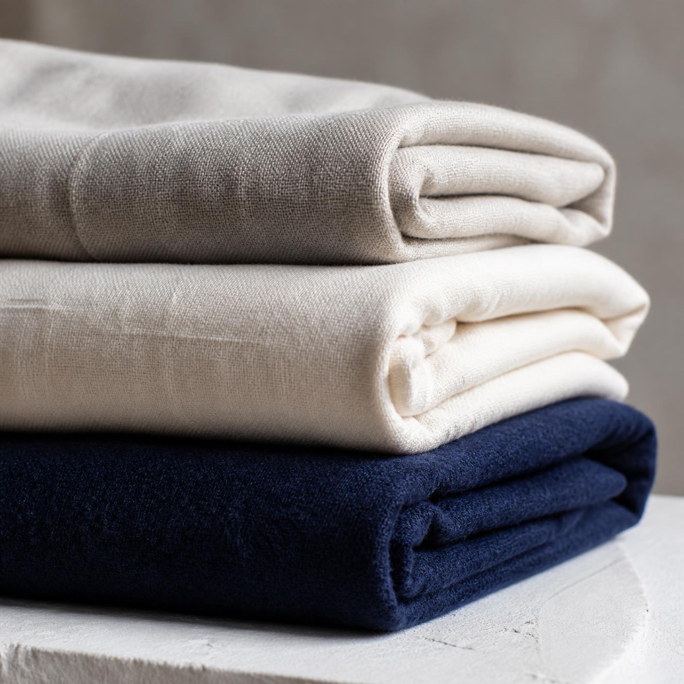 Interno del negozio: mani che piegano tessuti caldi appena stirati